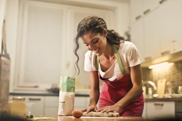 happy woman with rolling pin cooking in her green kitchen